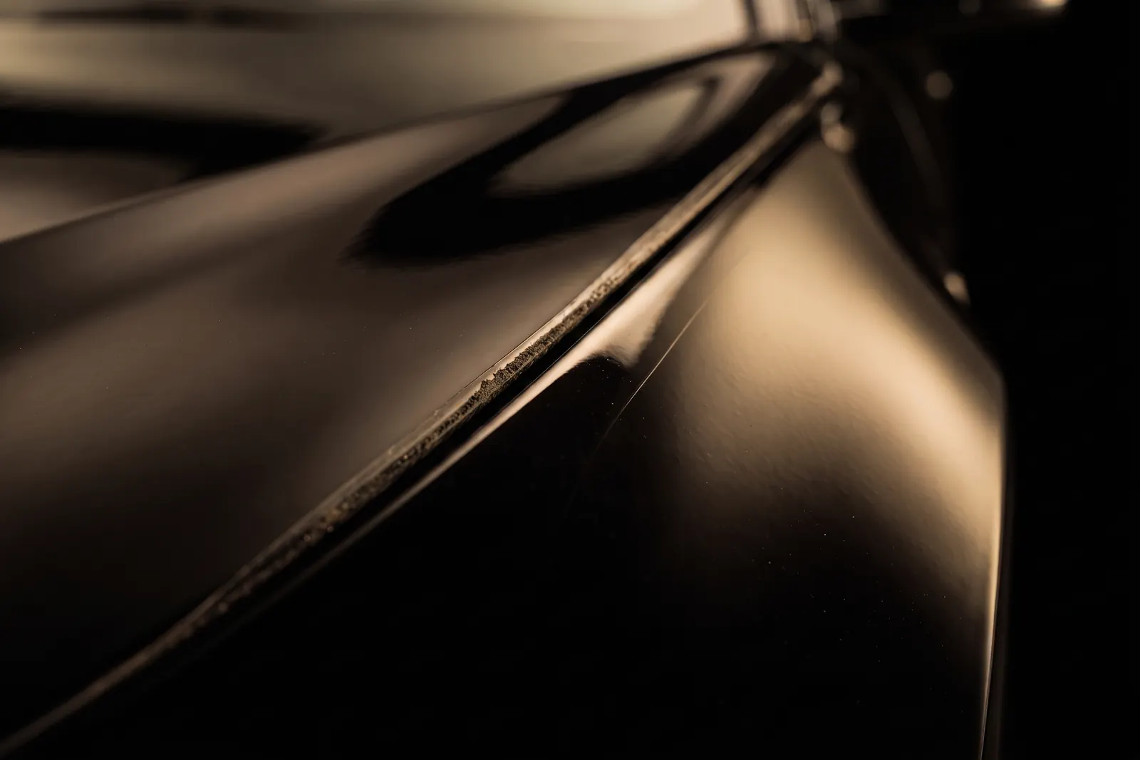 Macro of a hand-cut film edge stopping short of the panel, dirt collected along the lip