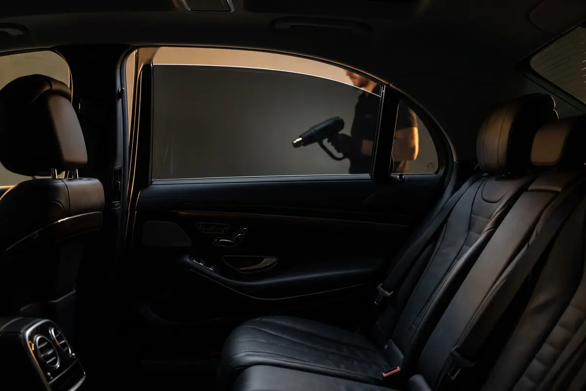 Ceramic window tint being heat-shrunk onto a luxury sedan side window